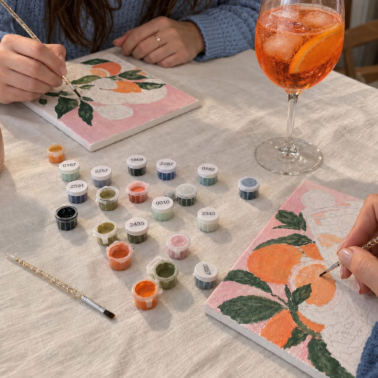 Penselen, verfpotjes en een schilderij met sinaasappels